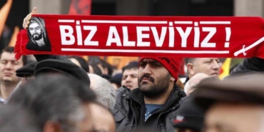 A protester holds a banner reading "we are alevi" as he and many others wait to hear the decision of the court in front of a courthouse in Ankara
